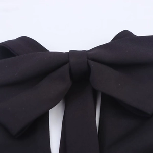 Gros plan sur la texture du tissu noir et le détail du nœud de cette robe courte dos nu
