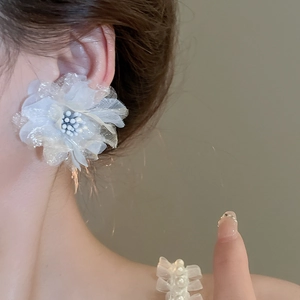 Detailed view of elegant white chiffon mesh flower earrings on model with soft lighting
