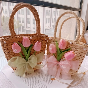 Detail of handmade straw bag with organza tulips, silk bow, and pearl chain accents
