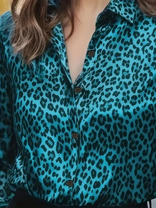 Detail view of teal leopard print satin shirt showing fabric texture and brown buttons