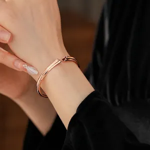 Rose gold open cuff bracelet with a red gourd charm on a model wrist against black velvet