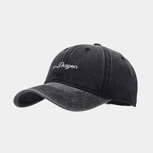 Close-up of a washed black denim baseball cap featuring white Dragon script embroidery