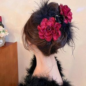 Detail of burgundy velvet rose and black feather hair claw clip on an elegant updo hairstyle