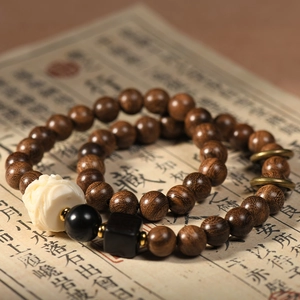 Double-loop sandalwood bracelet with carved white flower bead and natural wood grain