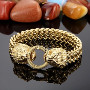 Detailed macro view of a gold lion head connector and thick woven link chain bracelet