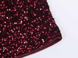 Detailed macro view of burgundy sequins on premium velvet fabric texture for party wear