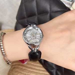 Close-up of a women's silver watch with black leather strap and rotating crystal dial