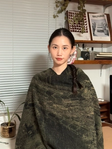 Dettaglio di uno scialle verde scuro con motivi etnici in finta cashmere sulla modella