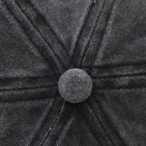 Macro view of the six-panel crown and top button on a washed cotton baseball cap