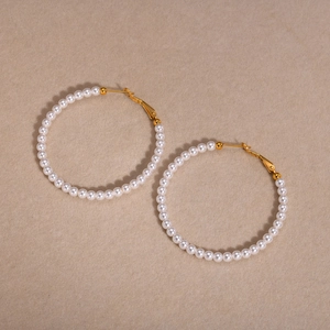 Close-up of gold-plated C-shaped hoop earrings with elegant white faux pearls