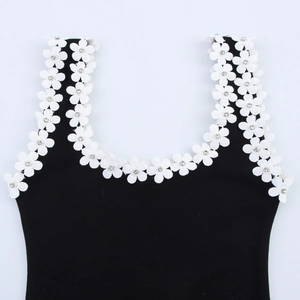 Dettaglio del top in maglia nera con fiori bianchi applicati e centro in strass