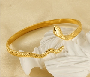 Detailed macro view of golden snake-shaped bracelet with intricate scale pattern engraving