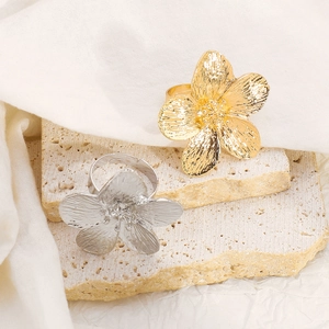 Detailed close-up of gold and silver floral rings with brushed metal texture