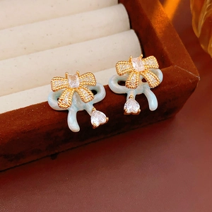 Close-up of bow earrings with mint blue enamel and white zircon heart drops