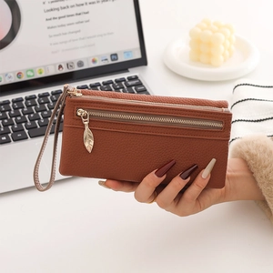 Macro view of brown lychee pattern leather wallet featuring a gold leaf-shaped zipper pull