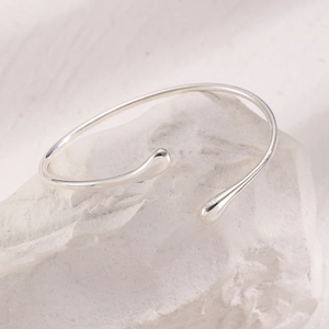 Detail of silver S925 lava open armband with liquid metal texture and teardrop design