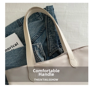 Detail of flat faux leather handles and stitching on this cream white tote bag