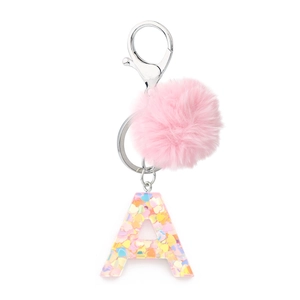Close-up of pink fluffy pom-pom and resin letter A keychain with colorful sequins