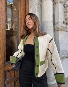 Detail of off-white quilted jacket with green and black trim and urban street style design