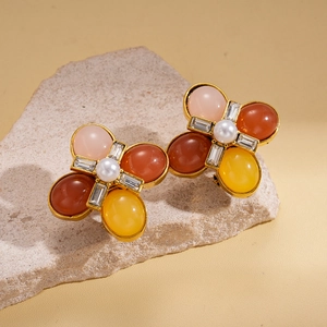 Détail de boucles d'oreilles fleuries avec pétales en résine et perle centrale