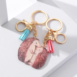 Detail of hedgehog couple keychains with gold clasps, colorful tassels and acrylic pendants