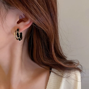 Close-up of a model wearing double-layered C-shaped gold earrings with black velvet chain