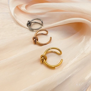 Three knot-shaped stainless steel rings in gold, rose gold, and silver on silk fabric