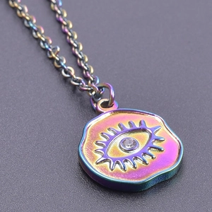 Macro shot of iridescent Evil Eye pendant with white rhinestone and 18k gold chain