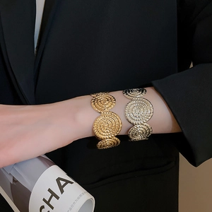 Detail of gold and silver metallic bangles with elegant spiral textures and wavy edges