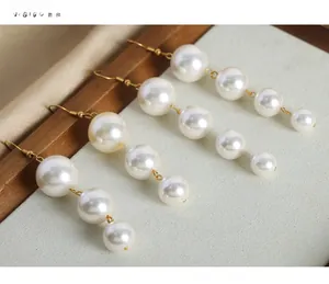 Macro detail of elegant vintage style pearl drop earrings with gold hooks on velvet