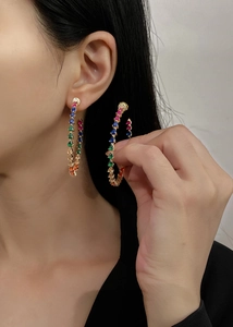 Close-up of gold hoop earrings with multi-color teardrop gemstones and vibrant stones