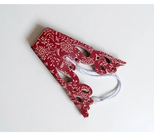 Close-up of red laser-cut paper snowflake with intricate white floral patterns