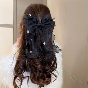 Détail d'une pince à cheveux en tulle noir avec cristaux sur cheveux ondulés
