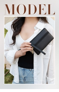 Detail of black pebbled leather ladies wristlet bag with dual zippers and handle