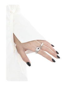 Detail of layered S925 silver textured ring bands with purple gemstone on female hand