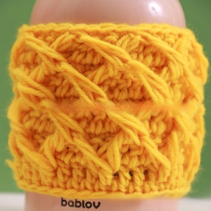 Macro shot of bright yellow hand-knitted diamond pattern texture on a cup sleeve