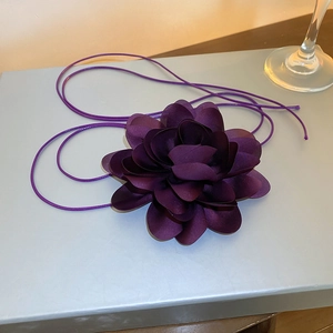 Detailed view of a handmade purple satin flower accessory with long silk ribbons