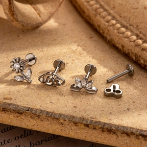Set of four silver G23 titanium labrets with zircon insets on a soft natural background