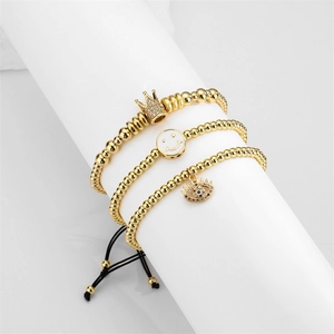 Set di tre braccialetti con perline dorate, ciondoli a corona, sorriso e malocchio