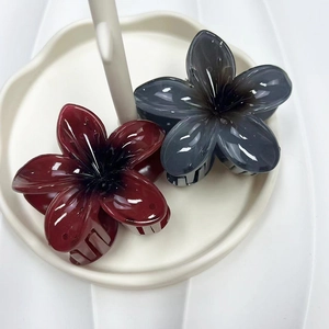 Detailed close-up of gradient resin flower hair claws in burgundy and grey on a white tray
