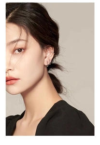 Close-up of minimalist silver hoop earrings and ear cuff on model ear lobe