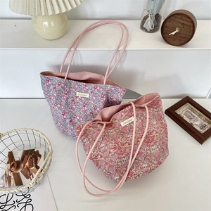 Détail de sacs fourre-tout en toile florale avec étiquette Sorakka et anses en corde rose