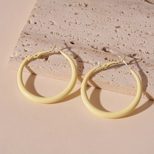 Close-up of minimalist light yellow geometric hoop earrings with smooth lacquer finish