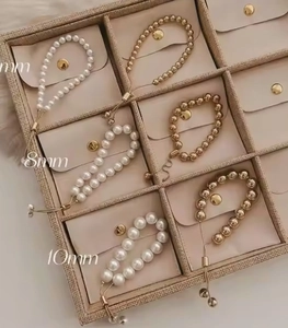 Close-up of gold and pearl beaded bracelets with adjustable sliders in a jewelry box