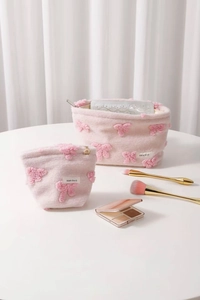 Detailed view of pink plush makeup bags in two sizes with 3D bows and metal zippers