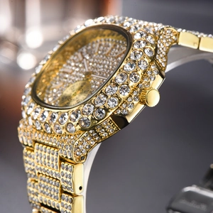 Vista macro di un orologio di lusso dorato con diamanti e quadrante nottilucente luminoso