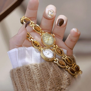 Close-up of vintage gold watches with tiger eye stones and elegant oval dials for women