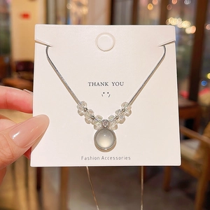Detailed view of silver bow necklace with translucent circular pendant on display card