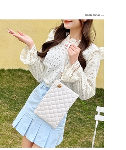 Chic white quilted mini bag featuring gold hardware and a top handle on a stylish model