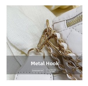 Macro detail of white quilted leather bag showing gold-tone metal hook and chain strap